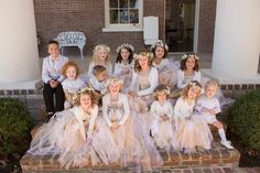 a group of young children dressed in white and pink dresses posing for a photo on the steps