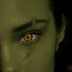 a close up of a person's face with yellow colored eyes and green skin