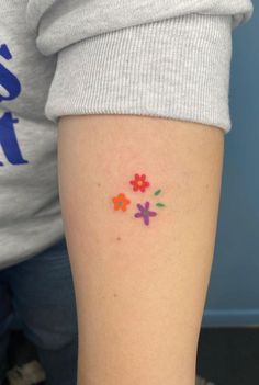 a woman's arm with colorful flowers on the left side of her body and an orange flower in the middle