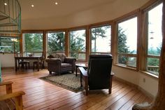 a living room filled with furniture and windows next to a spiral stair case in front of a large window