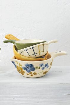 three ceramic bowls are stacked on top of each other and one has a spoon in it