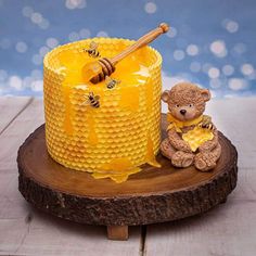 a small teddy bear sitting next to a honey jar on top of a wooden board