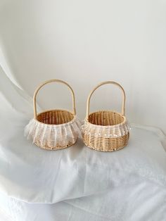 two wicker baskets sitting on top of a white sheet