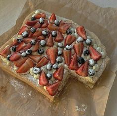 a pizza topped with strawberries and blueberries on top of parchment paper