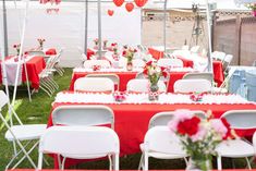 tables and chairs are set up for an outdoor event with hearts hanging from the ceiling