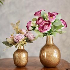 two gold vases with flowers in them on a table