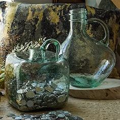 two glass vases sitting on top of a table filled with coins and other items