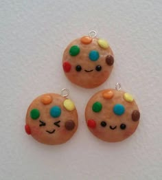 three cookies with different colored candies and faces on them are sitting next to each other