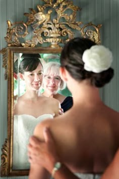 a woman looking at her reflection in the mirror while she is getting ready for her wedding