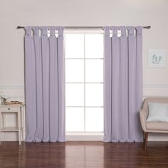 a living room filled with furniture and a window covered in purple drapes next to a white chair