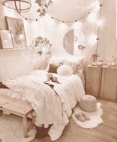 a bedroom with white walls and wooden flooring is lit by fairy lights, while a bed sits in front of a mirror on the wall