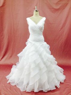 a white wedding dress on a mannequin stand in front of a red backdrop