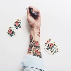 a woman's arm with flowers on it and some stickers next to her