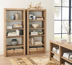 two wooden bookshelves with baskets and vases on them