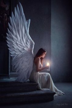 an angel sitting on steps holding a candle