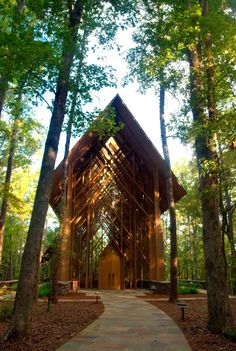 a wooden structure in the middle of some trees and dirt path with benches on either side