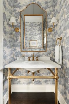 a bathroom with a sink, mirror and gold faucet