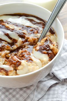 a white bowl filled with food next to a glass of milk on top of a table