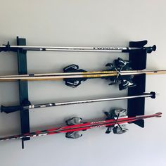 three skis are hanging on the wall next to two poles and one is upside down