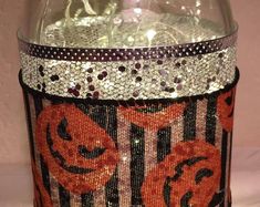 a glass jar filled with lots of different types of beads and sequins on it