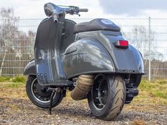 a grey scooter parked on top of a gravel field