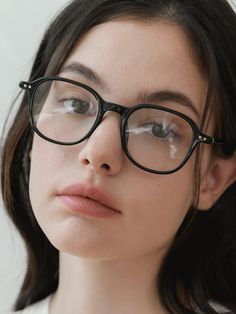 a young woman wearing glasses and looking off to the side with her head tilted forward