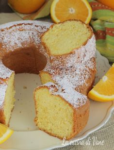 a cake with oranges and powdered sugar on top is sitting on a plate