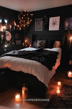 a black bedroom with candles lit up on the bed and pictures hanging from the wall