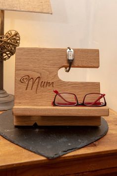 a pair of red glasses sitting on top of a wooden stand next to a lamp