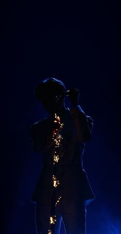 a man standing in the dark with his hands on his head and lights behind him