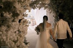 the bride and groom are walking down the aisle holding each other's hands as they walk towards their wedding ceremony