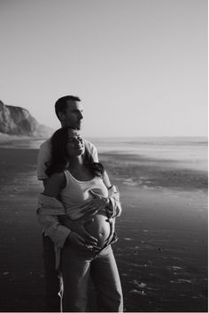 black and white photograph of a pregnant couple on the beach