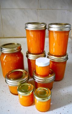 several jars filled with orange colored liquid on top of a counter