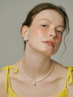 a woman wearing a yellow dress and pearl necklace