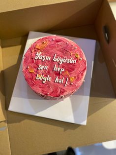 a birthday cake with pink frosting and writing on it sitting in a cardboard box