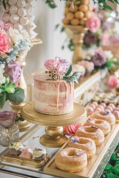 a table topped with lots of donuts and a pink cake covered in frosting