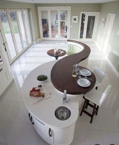 a kitchen with an island table and white chairs