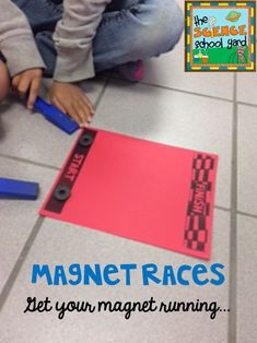 a child is playing with magnets on the floor in front of a red piece of paper