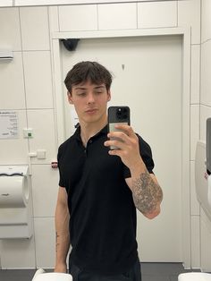 a man taking a selfie in front of two urinals with his cell phone