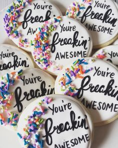 decorated cookies with words and sprinkles are on a white plate that says, you're freaking awesome