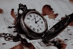 an old pocket watch sitting on top of sheet music with autumn leaves scattered around it