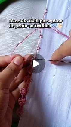 someone is using scissors to thread the fabric on a piece of cloth with pink yarn