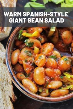 a bowl filled with beans next to bread