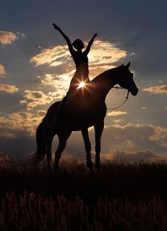 a woman riding on the back of a horse with her arms raised in the air