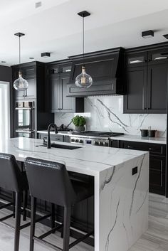 a kitchen with black cabinets and marble counter tops, two bar stools at the island