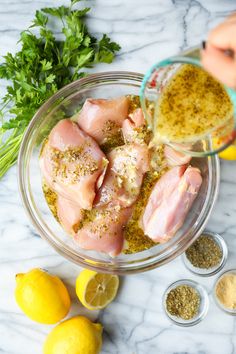 raw chicken in a bowl with seasoning and lemons