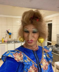 a woman with an elaborate make - up on her face and hair is standing in a kitchen