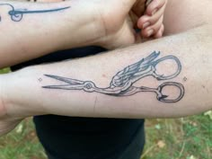 two people with tattoos on their arms holding scissors