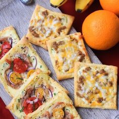 several small pizzas with toppings on them next to some oranges and bananas