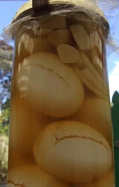 a jar filled with pickled onions sitting on top of a table next to a window